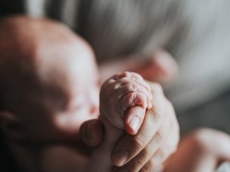 père tenant le pied d'un bébé